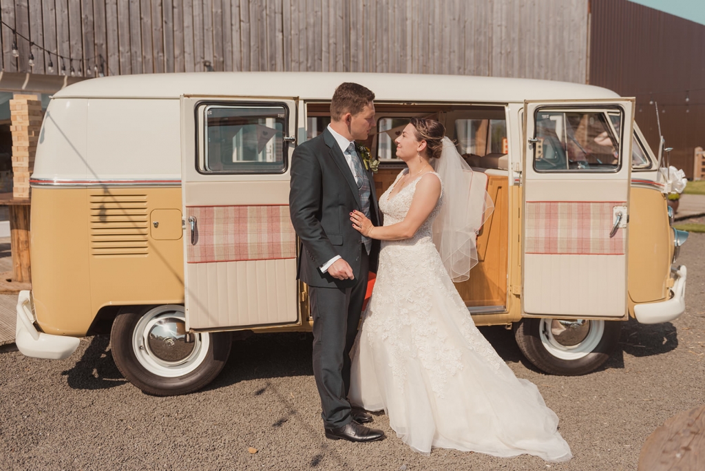 Husband and Wife look into each others eyes as newly married couple with Volkswagen back drop